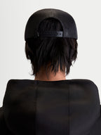 Alpinestars Boné Trucker Gravel, boné unissexo preto, vista traseira em modelo mostrando a malha respirável e o fecho snapback ajustável, sportswear casual.