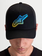 Alpinestars Boné Trucker Meteorite, boné de sportswear com traseira em malha, preto e azul, com emblema Astars texturado, coroa estruturada e pala curva, usado por um modelo.