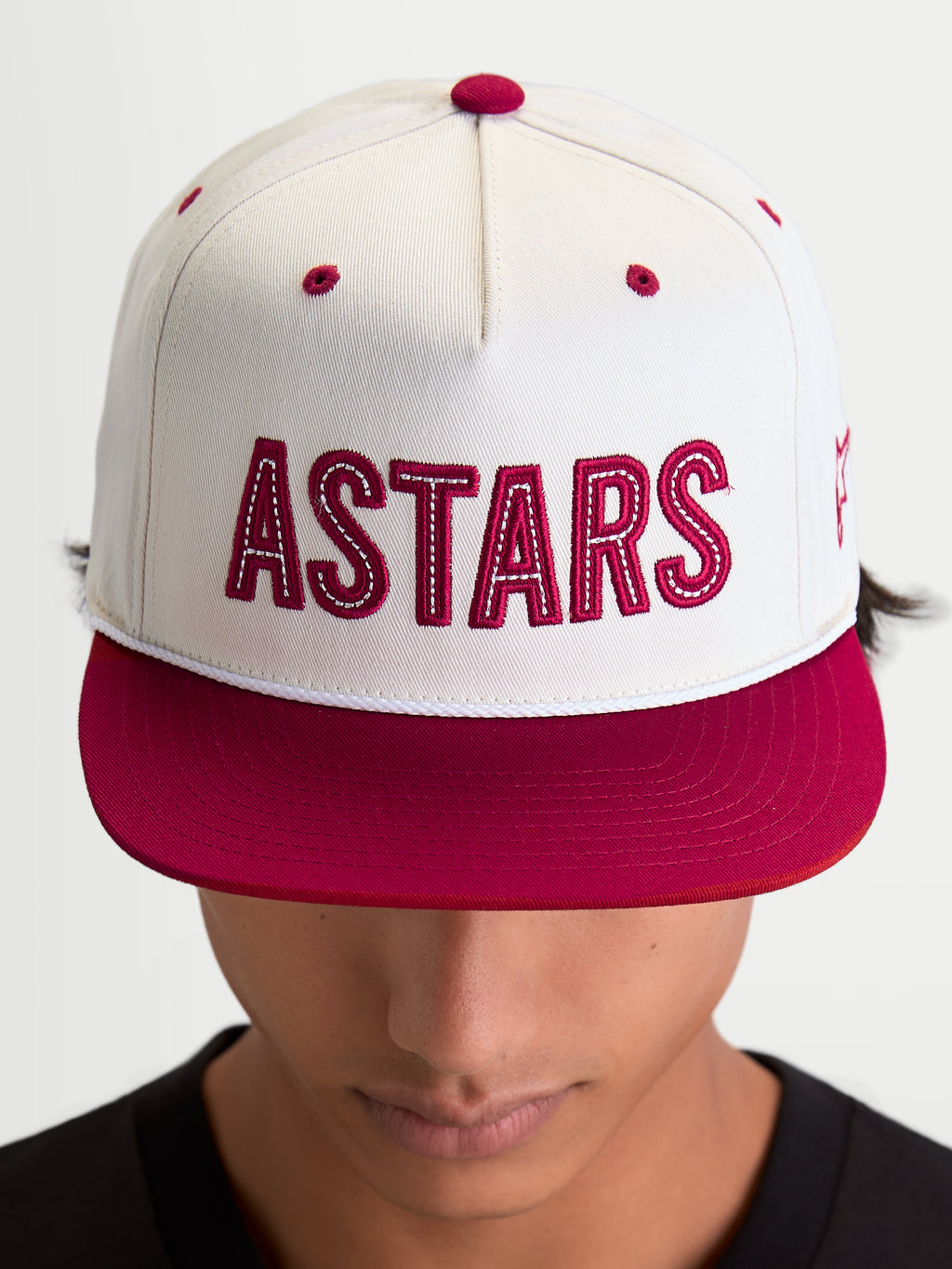 Alpinestars Boné Stadium Snapback, boné de estilo sportswear com aba plana e coroa estruturada, branco e vermelho, com logótipo frontal ASTARS em aplique e costuras contrastantes, visto num modelo.