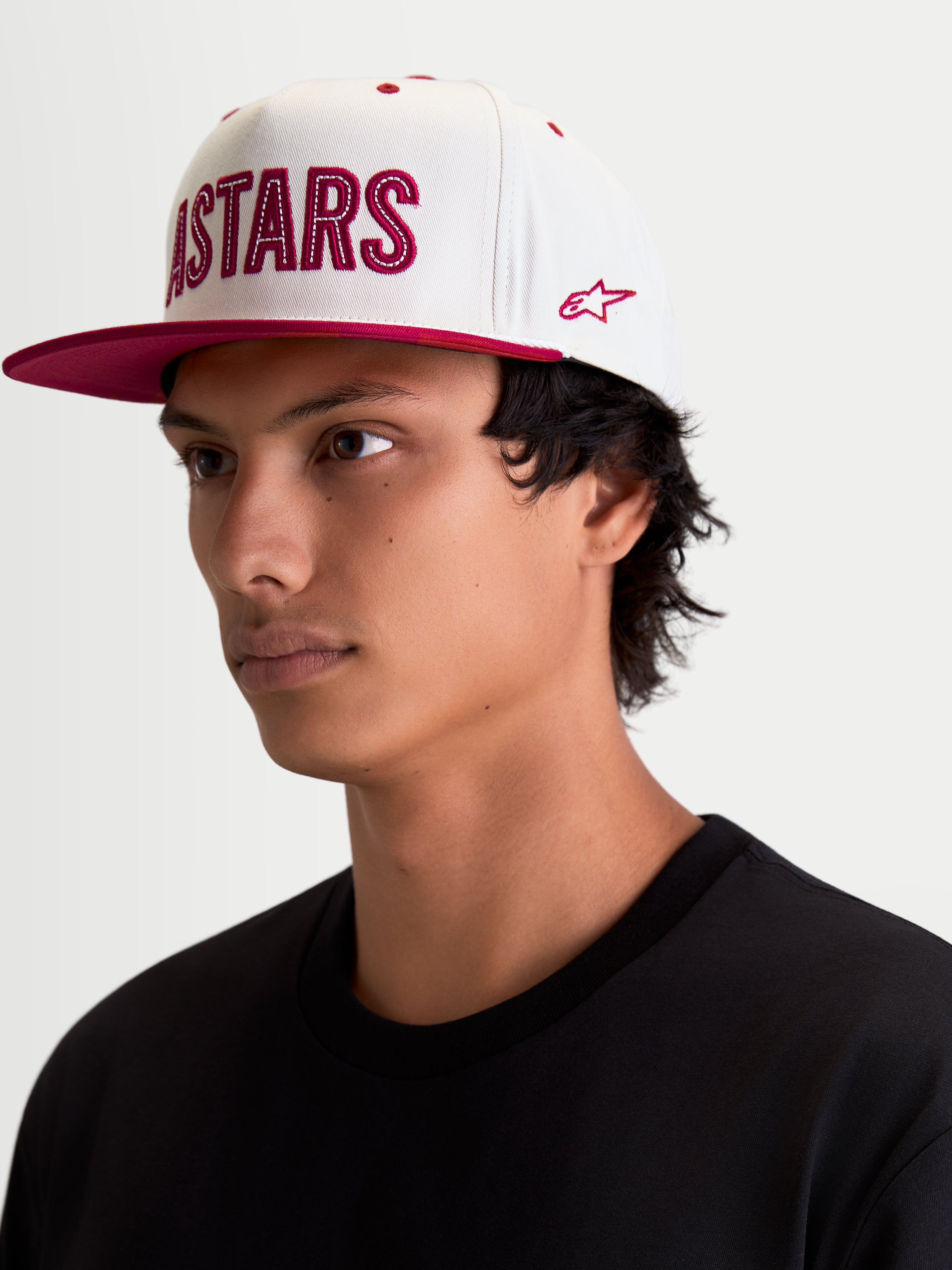 Alpinestars Stadium Snapback, boné sportswear lifestyle, branco e vermelho, com aba plana, coroa estruturada e aplique frontal do logótipo Astars com costura contrastante e bordado lateral, vista num modelo.