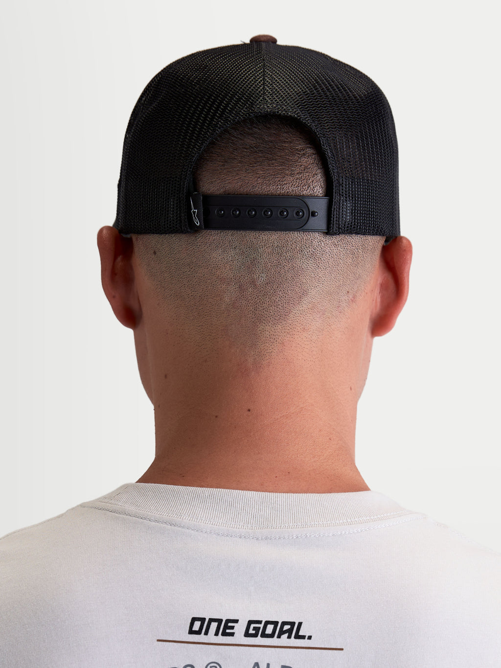 Alpinestars Boné Trucker Hotlink, boné unissexo castanho e preto, vista traseira no modelo com fecho snapback ajustável e painéis traseiros em malha para respirabilidade, casual sportswear.