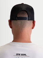 Alpinestars Boné Trucker Hotlink, boné unissexo castanho e preto, vista traseira no modelo com fecho snapback ajustável e painéis traseiros em malha para respirabilidade, casual sportswear.