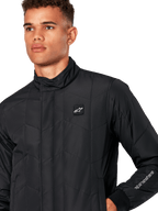 Alpinestars Precedent Jacket, Men's Quilted Sportswear Jacket in Black, close-up showing the low track collar, chest logo patch, and sleeve embroidery, featuring an iconic angled quilt pattern for a motorsport-inspired look.