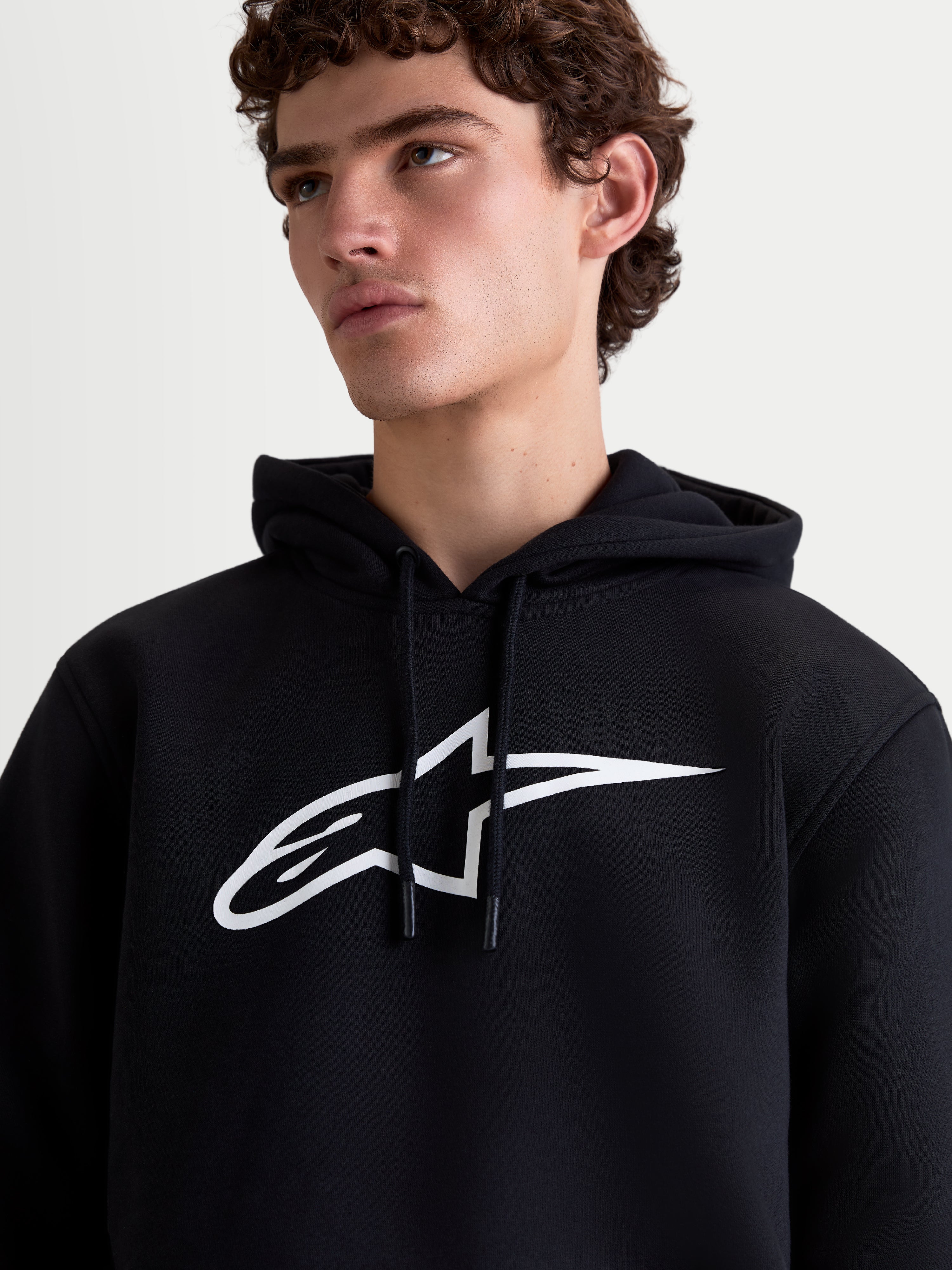 Camisola com capuz Ageless V3 Alpinestars, vestuário desportivo para homem em fleece, preta e branca, destaque para o logótipo branco no peito e capuz com cordão, vista de modelo.