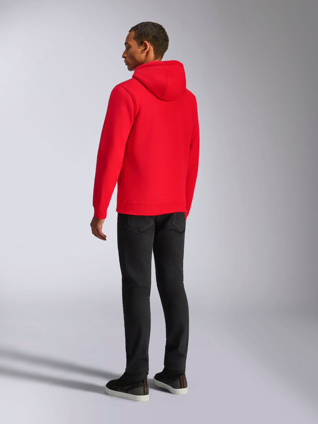 Alpinestars Ageless V3 Hoodie, streetwear casual, vermelho vibrante, vista traseira do modelo, com capuz forrado em jersey, punhos e bainha canelados, combinado com calças pretas, design moderno inspirado no desporto motorizado