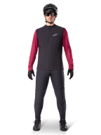 Alpinestars A-Dura Thermal Vest, Black cycling gilet worn over a maroon long-sleeve jersey, paired with dark grey MTB pants, black helmet and sunglasses, technical mountain bike apparel for cold-weather riding