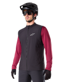 Alpinestars A-Dura Thermal Vest, Black, Cycling Thermal Gilet, worn over a maroon long-sleeve shirt, featuring a white chest logo, paired with a black MTB helmet and sunglasses, insulated performance layer for mountain biking