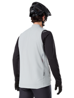 Alpinestars A-Dura Thermal Vest, Cinzento Titanium, vista traseira do modelo a usar uma camisola de manga comprida preta e capacete de BTT, design minimalista com pequeno logótipo de estrela vermelha nas costas, colete de ciclismo leve e isolado para condução fora de estrada
