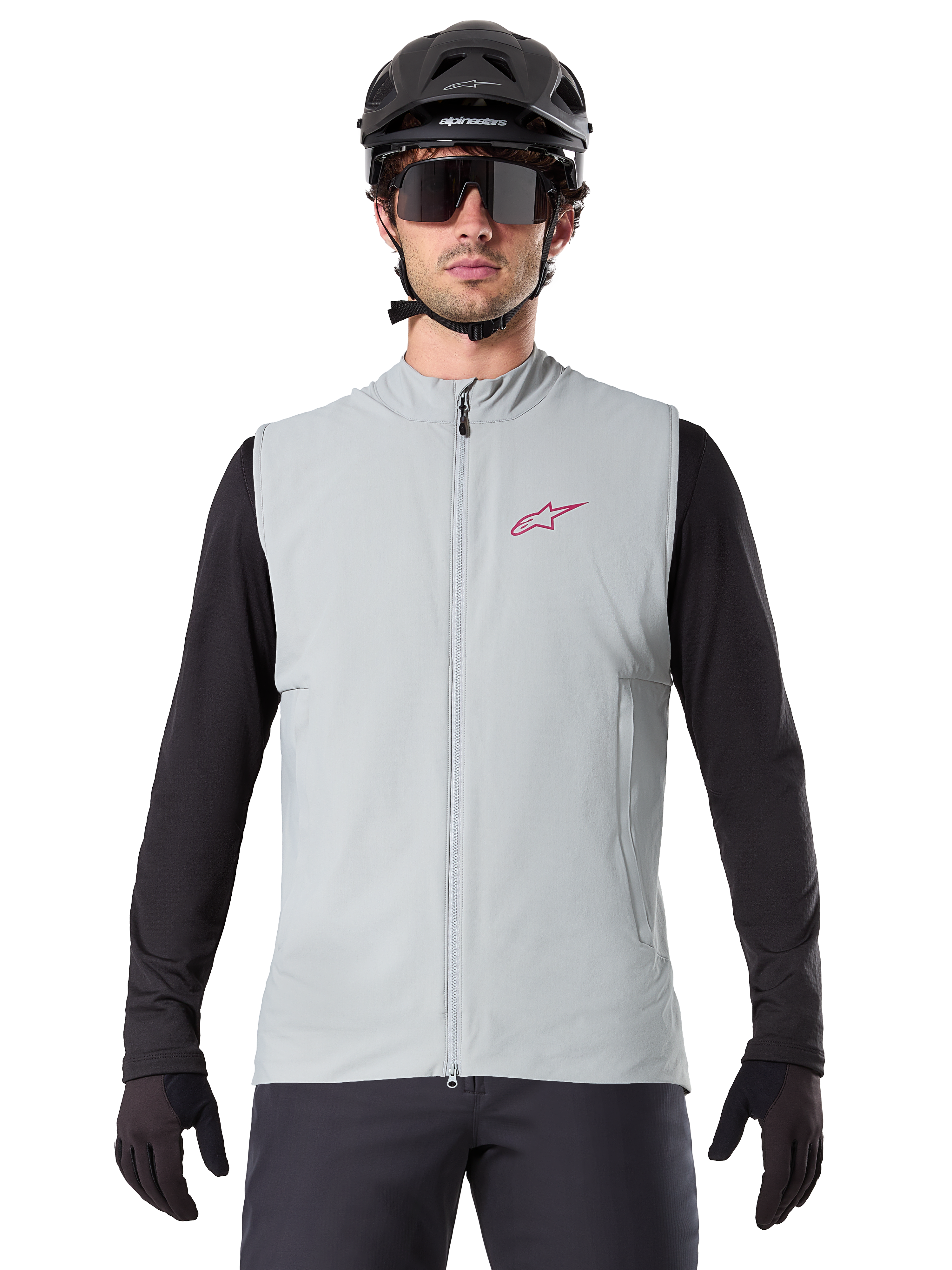 Colete Térmico Alpinestars A-Dura, colete de ciclismo, cinzento titanium, usado com uma camisola de manga comprida preta e capacete de ciclismo preto, logótipo da estrela Alpinestars vermelho no peito, leve e isolado para mountain biking.