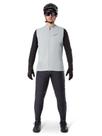 Alpinestars A-Dura Thermal Vest, colete de ciclismo, Cinzento Titanium, usado com camisola de manga comprida preta e calças pretas, capacete e óculos de sol pretos, com logótipo Alpinestars vermelho, isolamento térmico leve para mountain biking