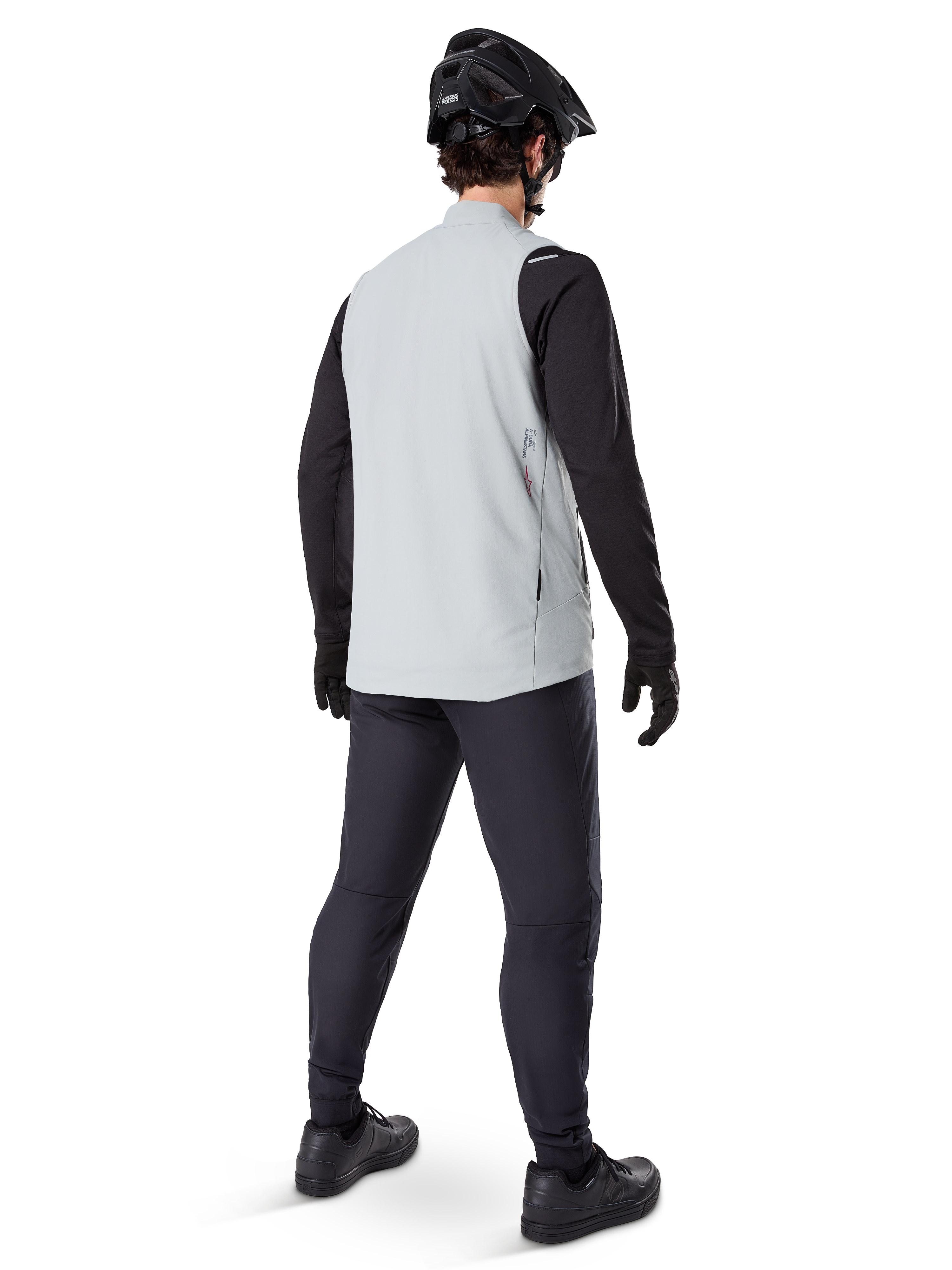 Alpinestars Colete Térmico A-Dura, Cinza Titanium, vista traseira de modelo a usar o colete de ciclismo com isolamento sobre uma camisola de manga comprida preta e calças escuras, com capacete de BTT e luvas pretas, concebido para ciclismo fora de estrada em climas frios