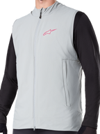 Alpinestars A-Dura Thermal Vest, colete de ciclismo isolado em cinzento Titanium, com logótipo de estrela cor-de-rosa no peito, usado sobre uma camisola preta de manga comprida, inclui um bolso vertical com fecho e fecho frontal completo, concebido para trilhos de BTT em climas frios