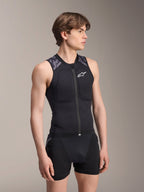 Colete de Proteção Alpinestars A-Motion Plasma, colete de proteção para MTB, camuflado preto, design em malha sem mangas com fecho central e acolchoamento no peito, detalhes camuflados cinzentos nos ombros, usado por um modelo masculino num cenário de estúdio.