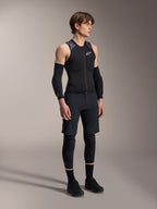 Alpinestars A-Motion Plasma Protection Vest, colete de proteção de BTT sem mangas em preto e camuflado, vista de corpo inteiro de modelo a usar o colete com manguitos e joelheiras, frente com fecho de correr e logótipo Alpinestars branco, equipamento de alta performance para mountain biking