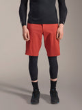 Alpinestars A-Motion Plasma Knee Sleeve, joelheira de proteção para MTB preta, usada com calções vermelhos e camisola de manga comprida preta, design ergonómico de perfil fino, construção em malha leve para condução off-road