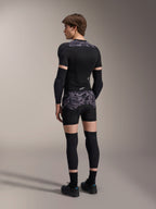 Modelo a usar os Boxers de Proteção Alpinestars A-Motion Plasma em Black Camo e o casaco de proteção A-Motion Plasma a condizer, vista traseira mostrando o padrão de camuflagem cinzento, cotoveleiras, joelheiras e sapatos de ciclismo, conjunto completo de equipamento de proteção para mountain bike