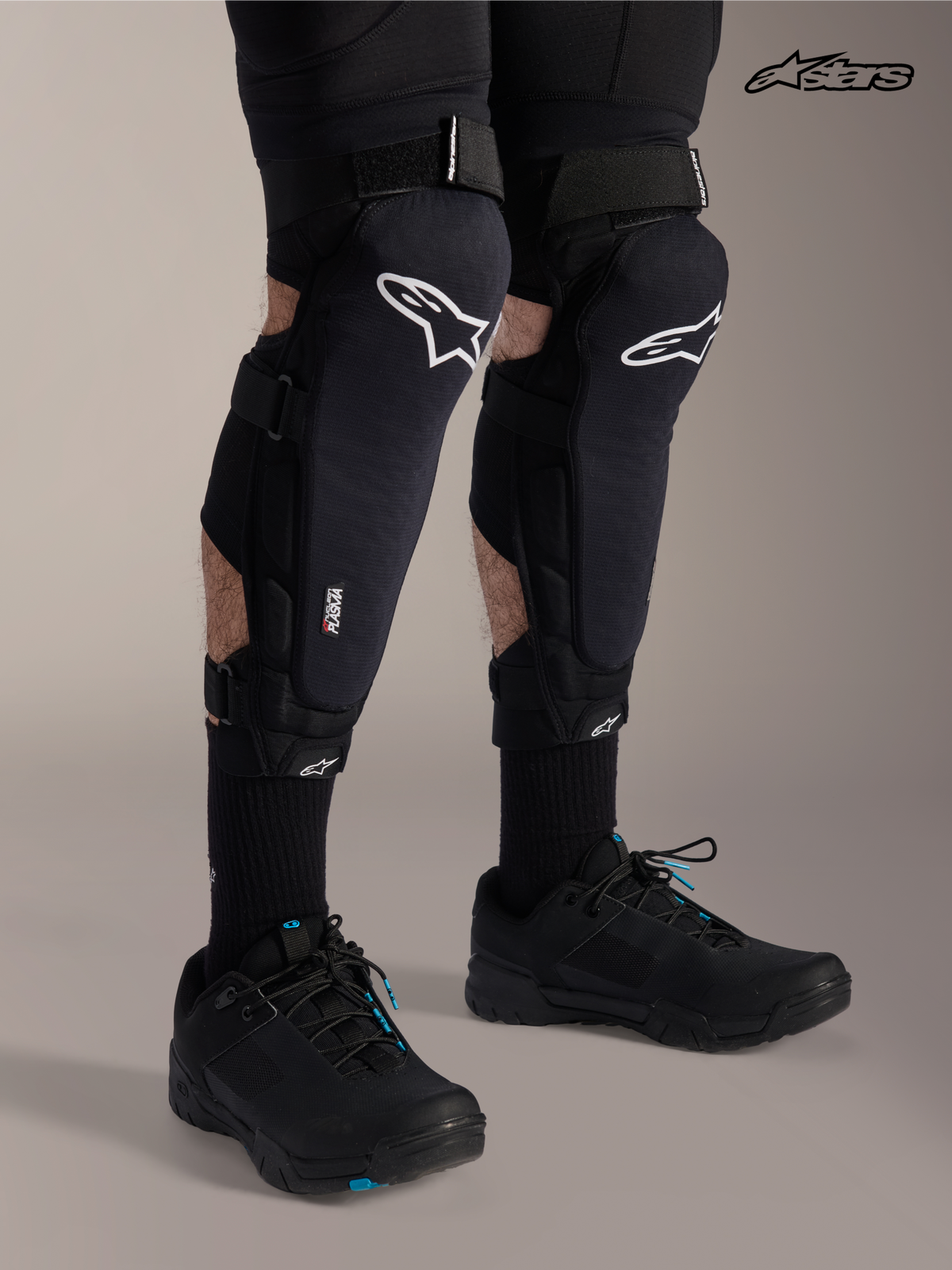 Alpinestars A-Impact Plasma Pro Knee Shin Protectors, mountain bike knee guards in black with white logo, worn by a model showcasing triple strap closure and Nucleon Plasma protection