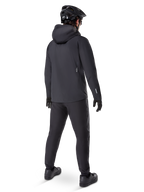 Alpinestars A-Dura Waterproof Pants, MTB pants, Black, shown from the rear on a rider wearing a full black mountain biking outfit including a hooded jacket and helmet, durable waterproof gear for muddy trails