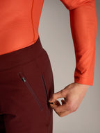 Calções Alpinestars A-Dura Ride bordeaux, pormenor de mão a abrir o bolso lateral com fecho e forro em malha.