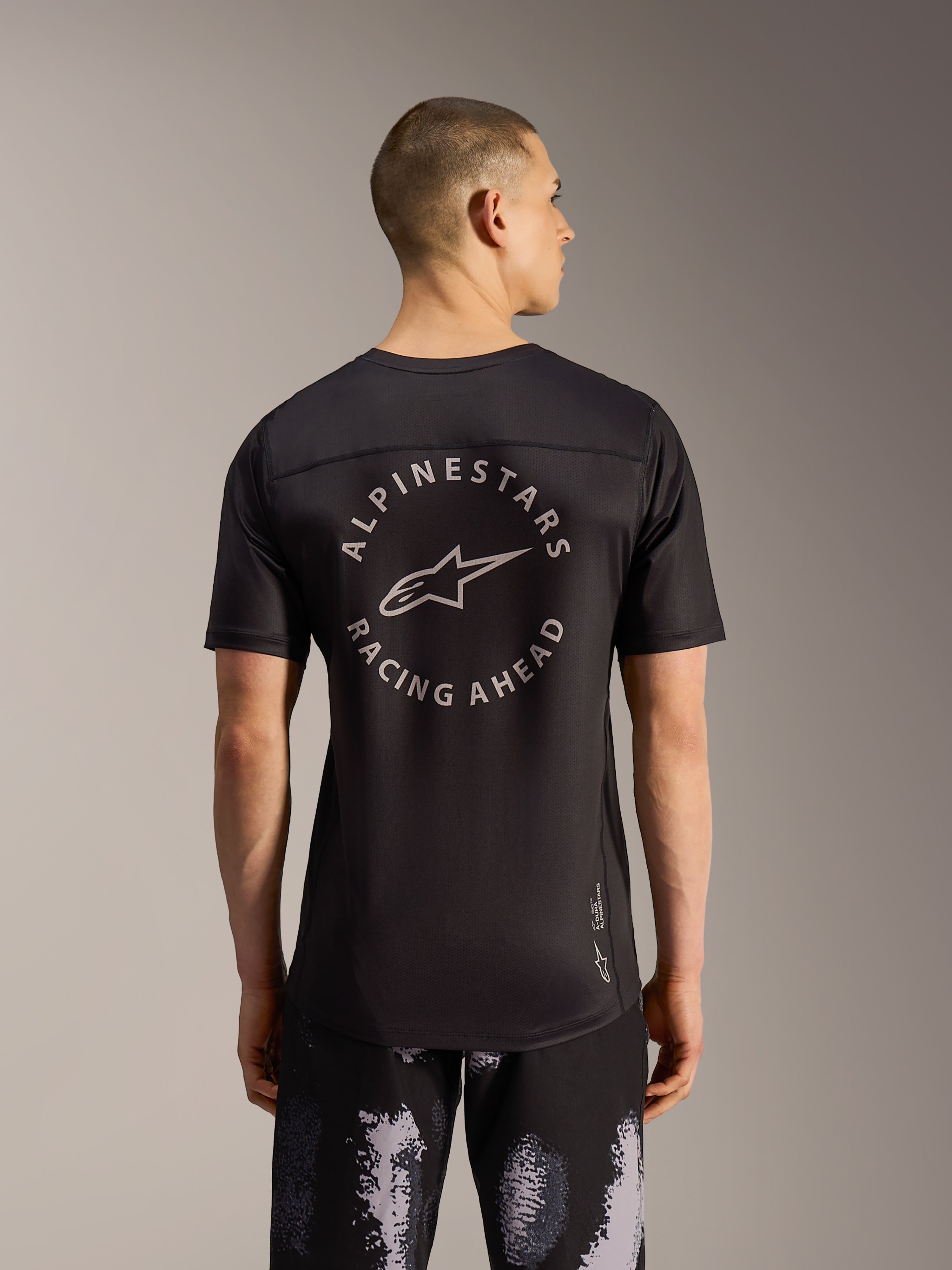 Calções Alpinestars A-Dura Ride Black Camo e jersey MTB preta com logótipo circular, vista posterior num modelo.