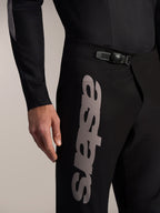 Calças Alpinestars A-Supra Elite pretas para BTT, com fecho de catraca na cintura e logótipo Astars cinzento na coxa.