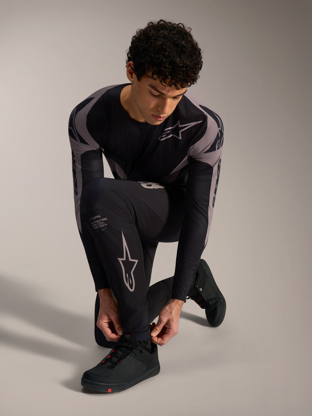 Calças Alpinestars A-Supra Elite pretas com logótipos cinzentos, modelo ajoelhado para BTT de alta performance.