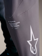 Calças A-Supra Elite em cinzento desbotado, com logótipo Alpinestars branco e o lema de corrida One Goal. One Vision.