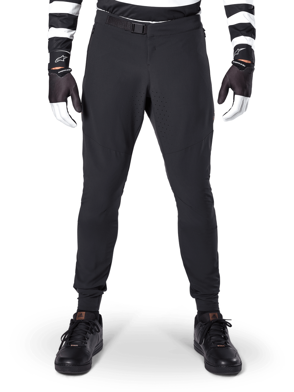 Alpinestars A-Aria Elite Pants, calças de mountain bike, pretas, vista frontal com perfurações a laser e fecho de fivela magnética, usadas com camisola às riscas pretas e brancas e luvas pretas, equipamento de ciclismo de performance para trilhos