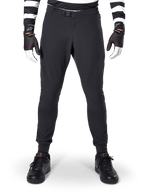Alpinestars A-Aria Elite Pants, calças de mountain bike, pretas, vista frontal com perfurações a laser e fecho de fivela magnética, usadas com camisola às riscas pretas e brancas e luvas pretas, equipamento de ciclismo de performance para trilhos