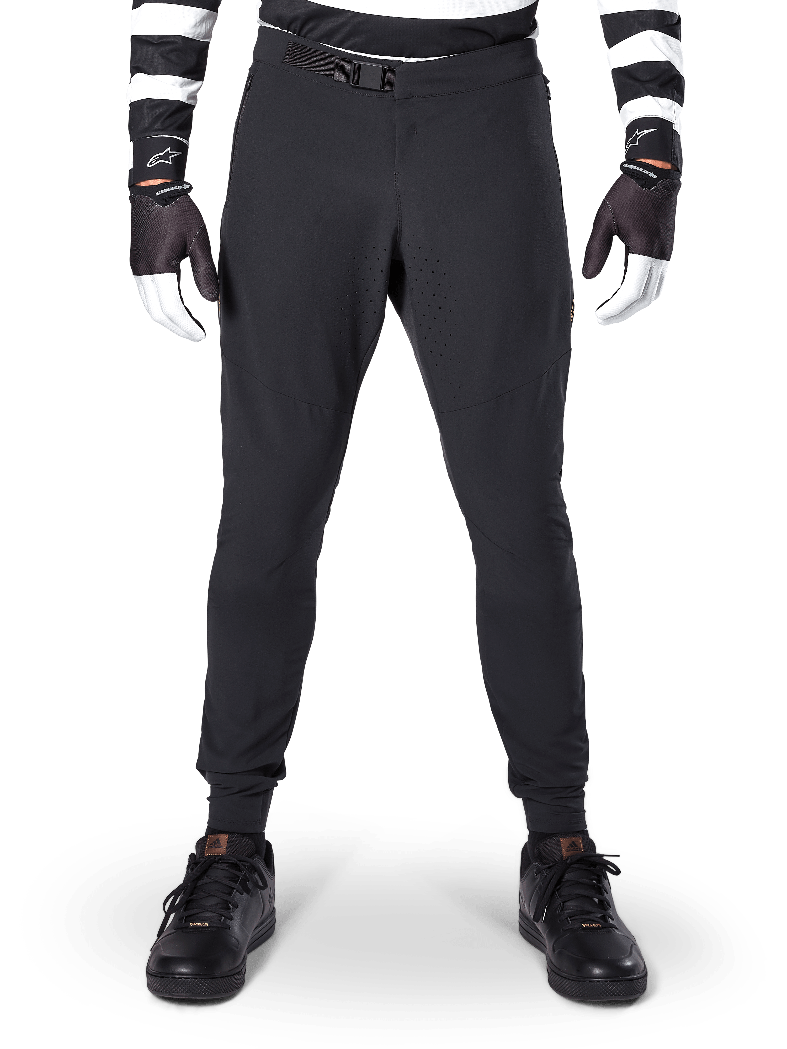 Alpinestars A-Aria Elite Pants, calças de mountain bike, pretas, vista frontal com perfurações a laser e fecho de fivela magnética, usadas com camisola às riscas pretas e brancas e luvas pretas, equipamento de ciclismo de performance para trilhos