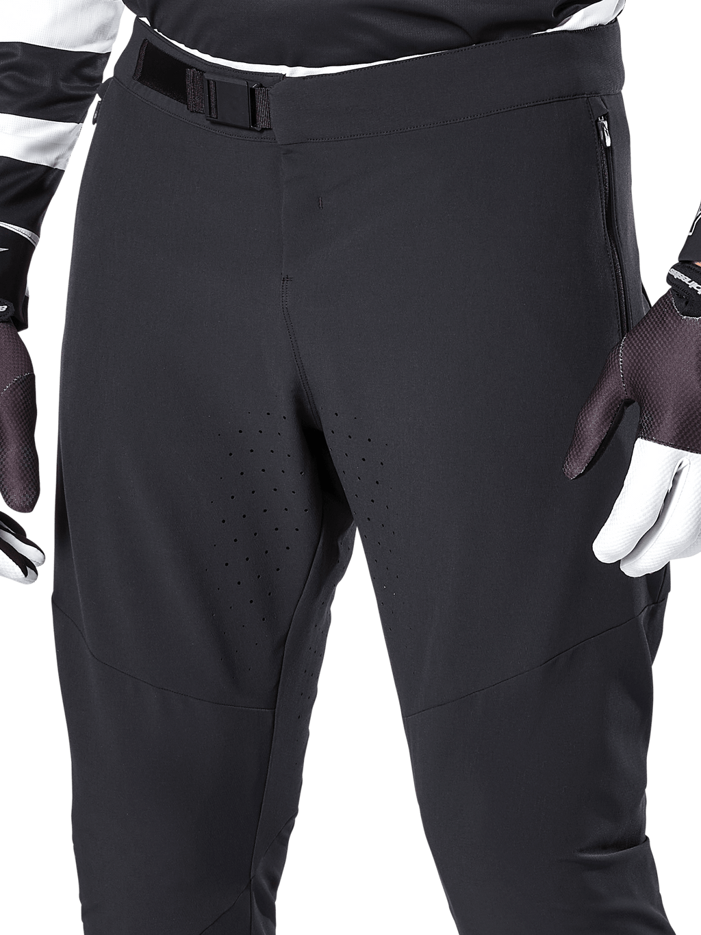 Alpinestars A-Aria Elite Pants, calças de mountain bike pretas, grande plano da zona da cintura e coxas com fecho de fivela magnética e perfurações a laser, combinadas com luvas de ciclismo