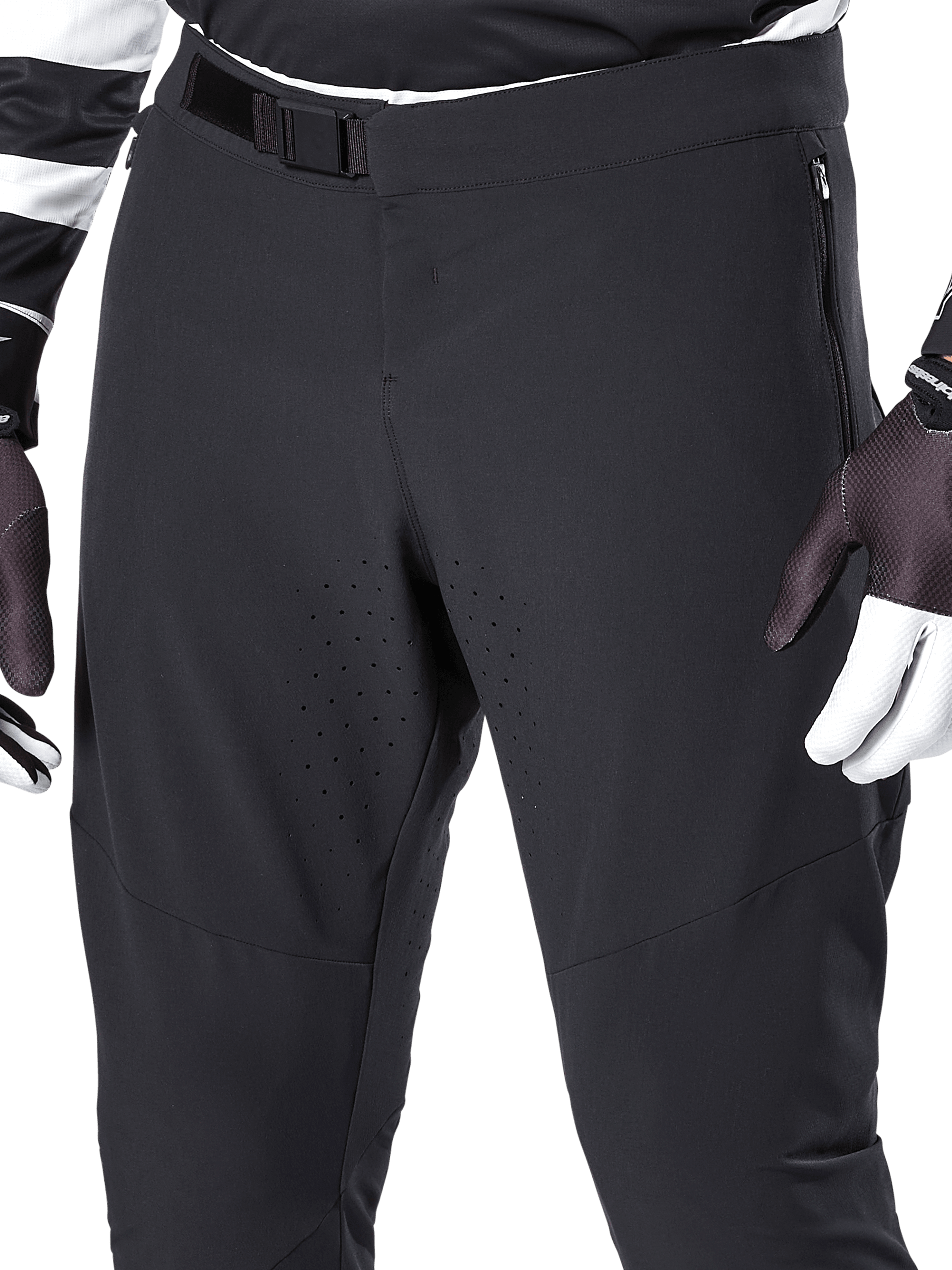 Alpinestars A-Aria Elite Pants, calças de mountain bike pretas, grande plano da zona da cintura e coxas com fecho de fivela magnética e perfurações a laser, combinadas com luvas de ciclismo