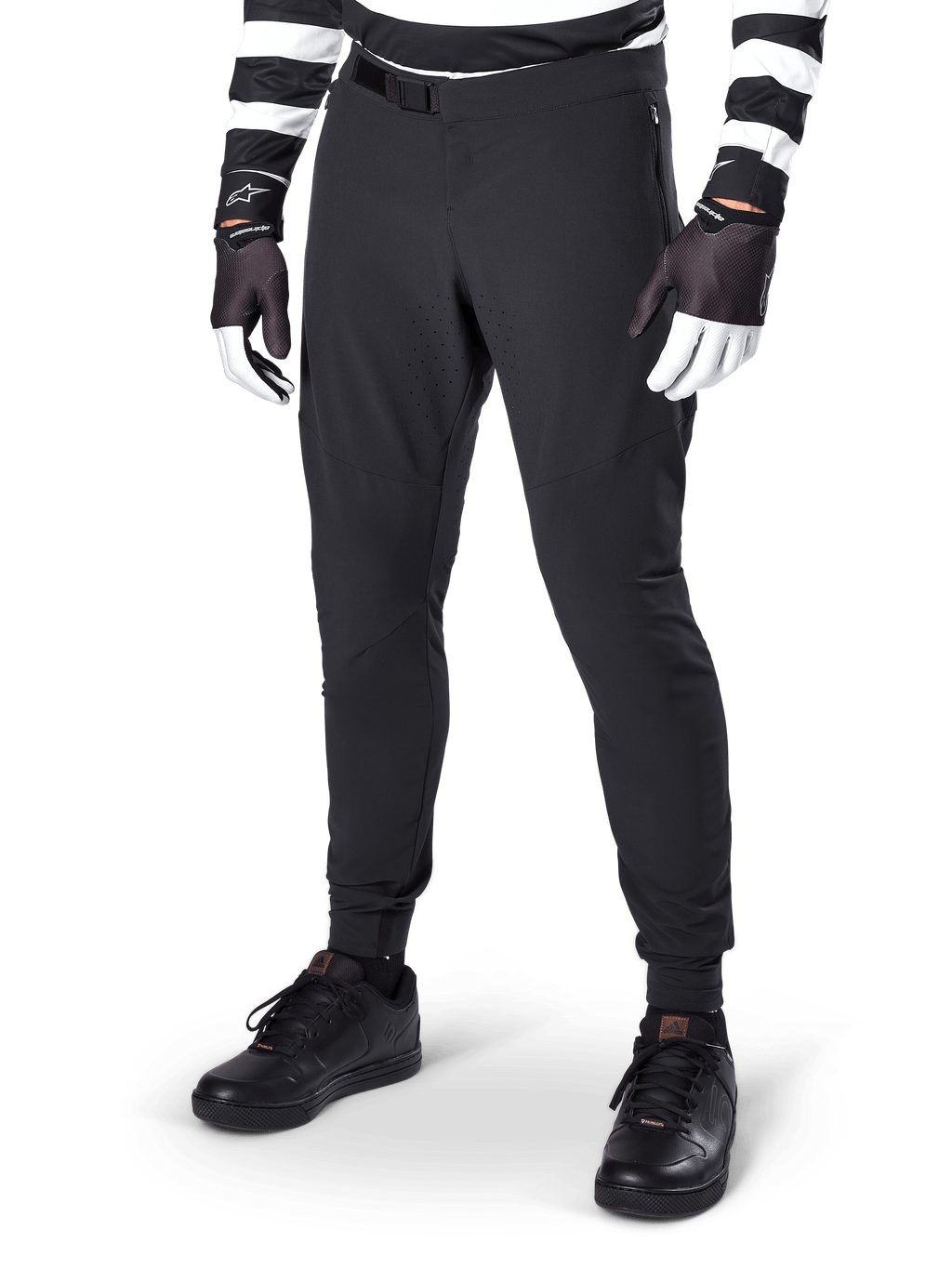 Alpinestars A-Aria Elite Pants, calças pretas de BTT, com ventilação cortada a laser nas coxas e fecho de fivela magnética, usadas com camisola e luvas às riscas pretas e brancas, equipamento de BTT de performance para ciclismo todo-o-terreno