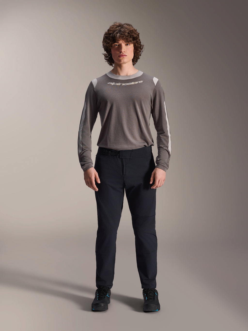 Calças Alpinestars A-Dura Elite, calças pretas de mountain bike, vestuário técnico de ciclismo com ajuste regular, usadas com uma camisola cinzenta de manga comprida e sapatos pretos, construção durável em Cordura® para condução fora de estrada