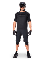 Ciclista de BTT masculino a usar os calções Alpinestars A-Aria Elite em preto, combinados com uma camisola de manga curta Alpinestars preta a condizer, capacete, luvas e joelheiras pretas, conjunto completo de equipamento de ciclismo off-road