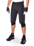 Alpinestars A-Aria Shorts, calções de BTT, pretos, pelo joelho com bolsos frontais com fecho e fivela de catraca ajustável na cintura, usados com joelheiras pretas, meias e luvas de ciclismo