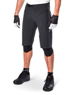 Alpinestars A-Aria Shorts, calções de BTT, pretos, pelo joelho com bolsos frontais com fecho e fivela de catraca ajustável na cintura, usados com joelheiras pretas, meias e luvas de ciclismo