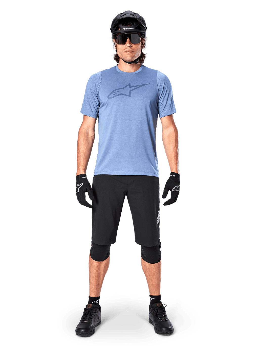 Calções Alpinestars A-Dura Elite, calções pretos de mountain bike, usados com uma t-shirt azul-claro, capacete preto, óculos de sol e joelheiras, vestuário profissional de ciclismo fora de estrada