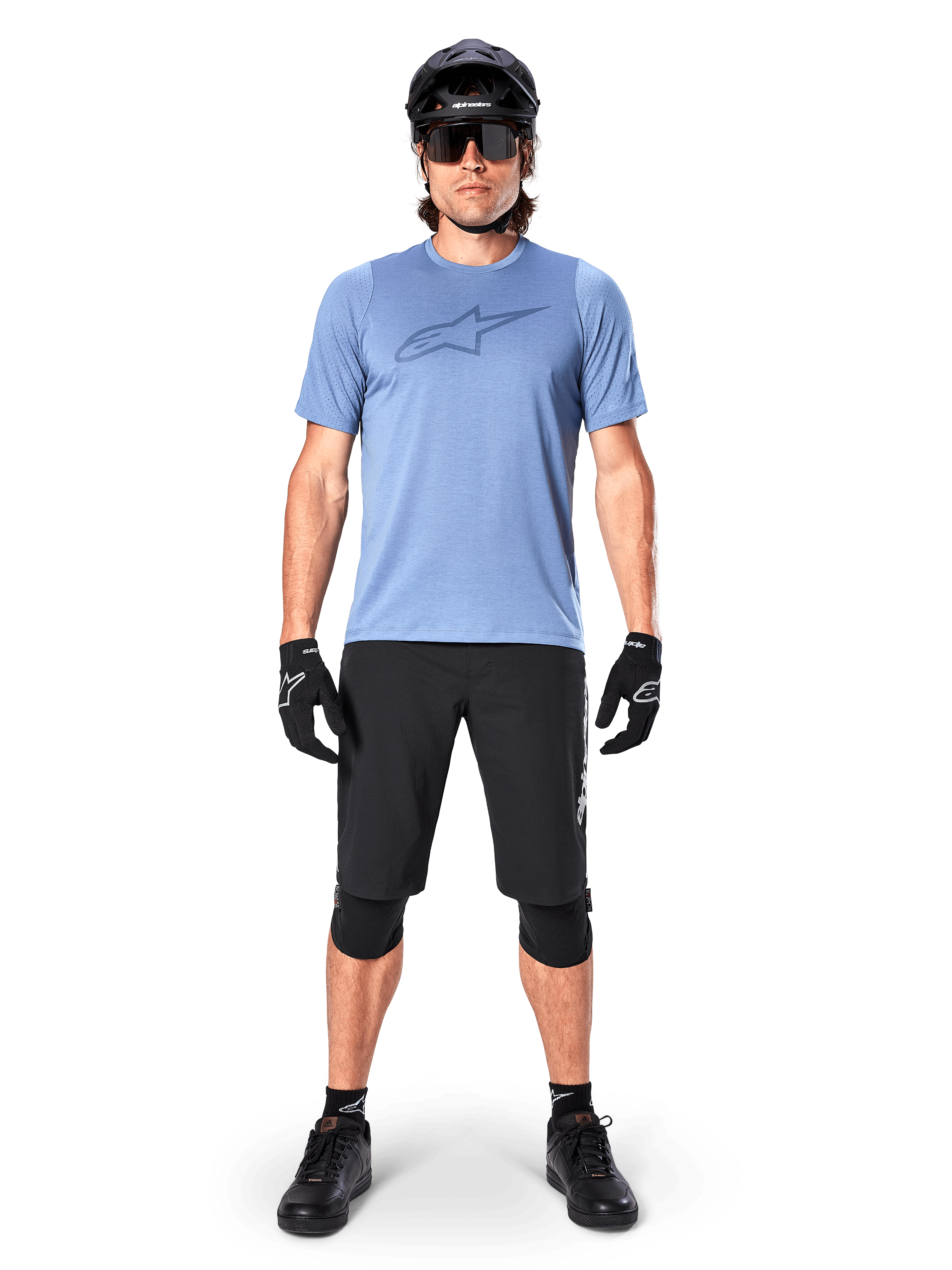 Calções Alpinestars A-Dura Elite, calções pretos de mountain bike, usados com uma t-shirt azul-claro, capacete preto, óculos de sol e joelheiras, vestuário profissional de ciclismo fora de estrada