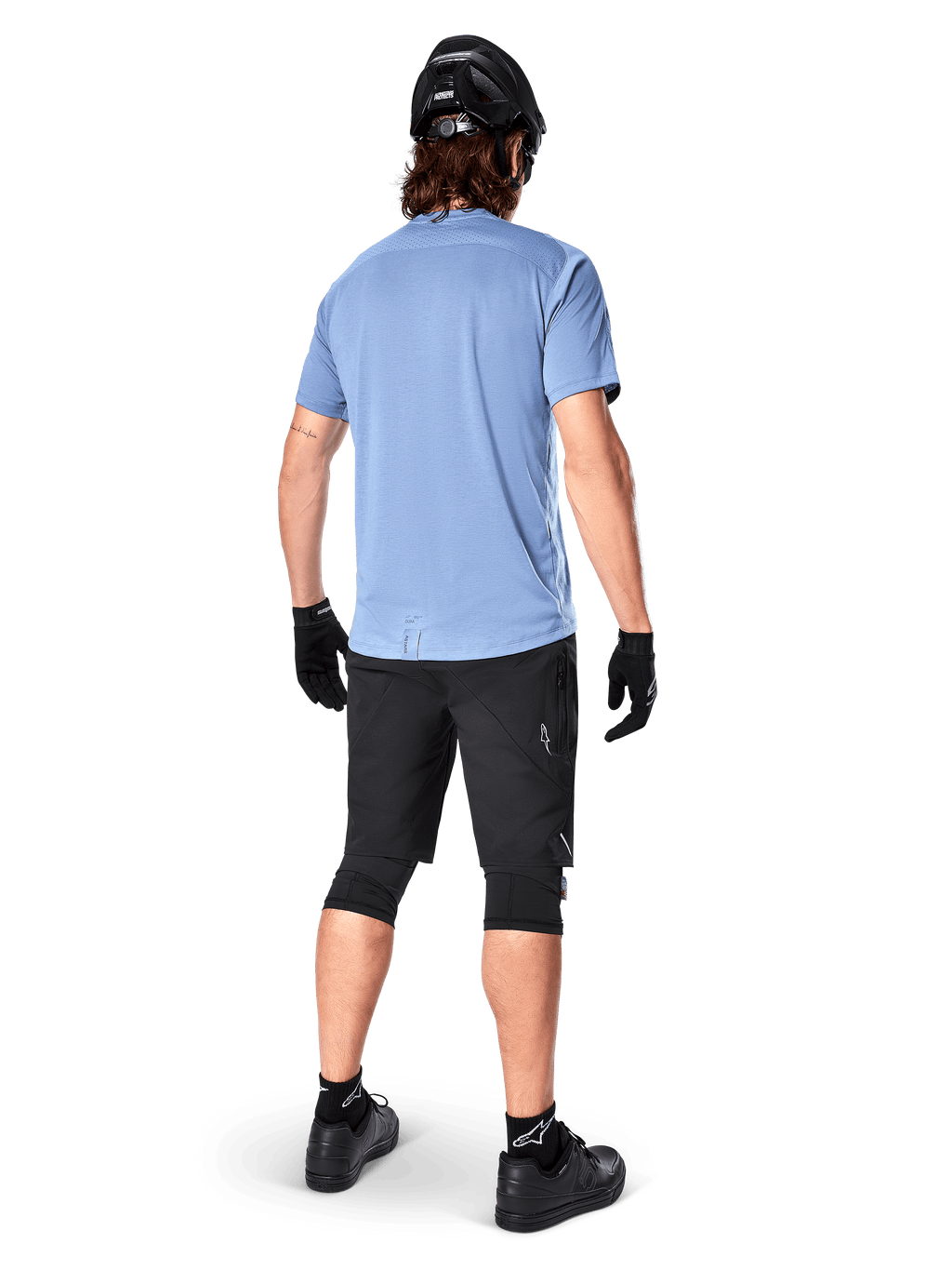 Calções Alpinestars A-Dura Elite, calções de BTT, pretos, vista traseira no modelo, usados com camisola de manga curta azul-claro e equipamento de proteção preto, design técnico com bolsos com fecho e detalhes refletores para ciclismo fora de estrada