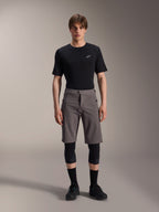 Alpinestars A-Dura Elite Shorts, calções de BTT cinzento escuro, usados com t-shirt preta de gola redonda e joelheiras pretas, vestuário de ciclismo de performance pelo joelho com fecho frontal de mola e tecido Cordura durável