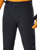 Alpinestars A-Dura Pants, Black MTB cycling pants, close-up view featuring double snap waist closure, adjustable side cinch, and zippered pockets, paired with an orange jersey and gloves