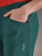 Calças Alpinestars A-Dura em verde Dark Pine, grande plano do bolso com fecho de correr e mão, com o logótipo e a marca Alpinestars em branco na coxa, calças de ciclismo MTB duráveis