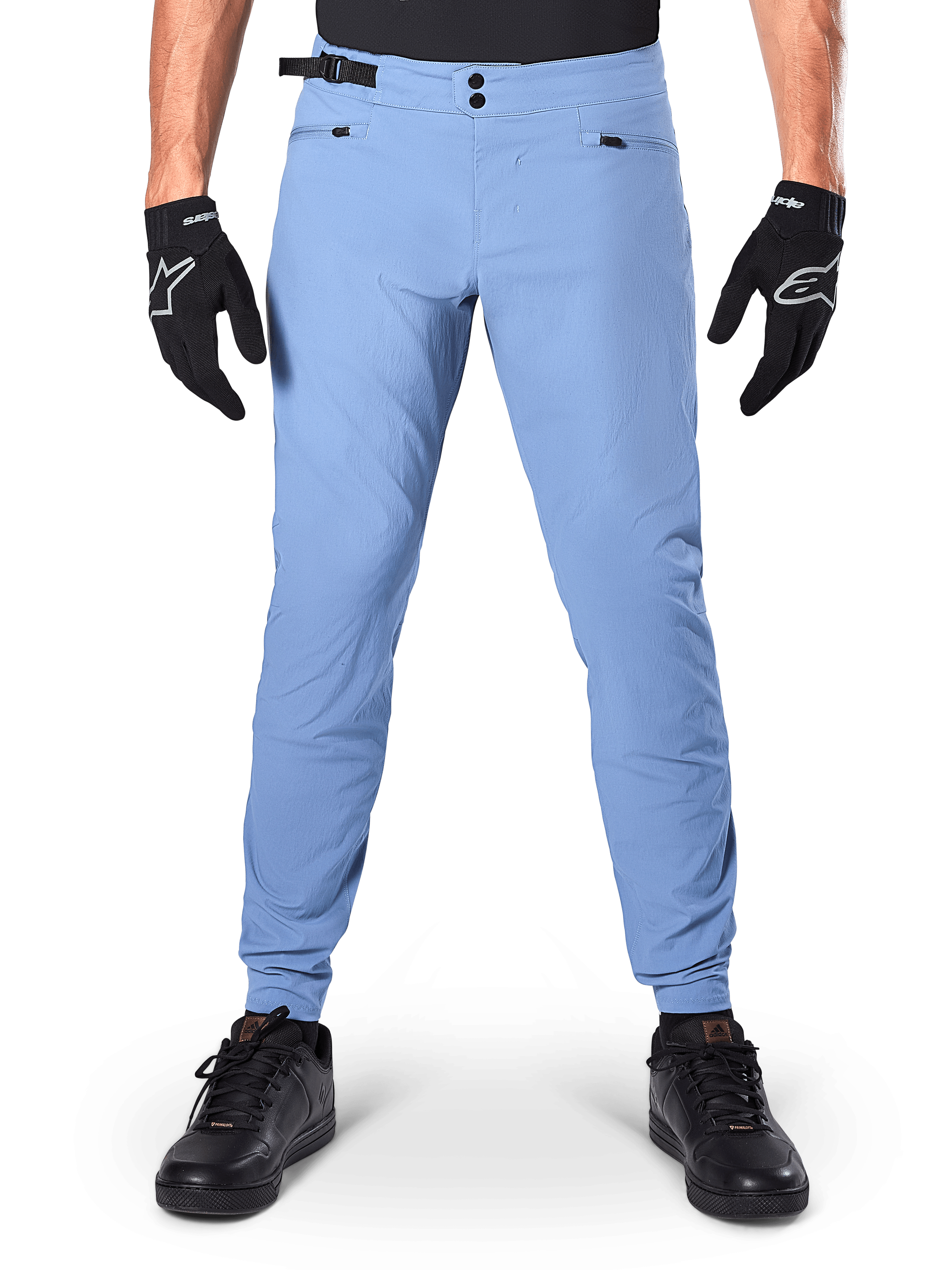 Calças Alpinestars A-Dura, calças de MTB, Infinity Blue, calças de mountain bike em azul claro com fecho de pressão duplo e bolsos com zíper, usadas com luvas pretas e sapatos pretos, ajuste regular com punhos elásticos