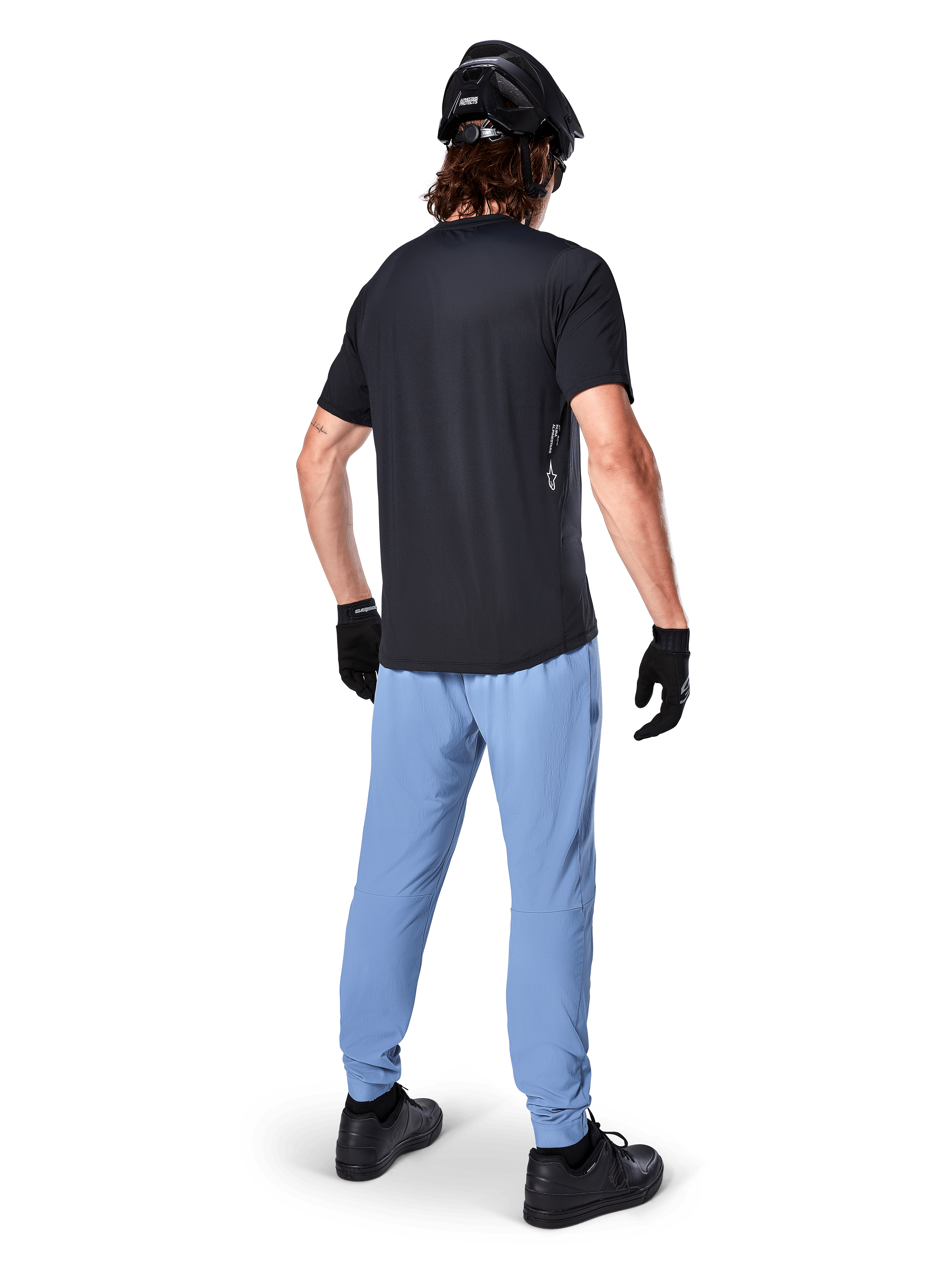 Calças Alpinestars A-Dura, calças de BTT, Infinity Blue, vista traseira de modelo a usar t-shirt preta e capacete de ciclismo preto, com tecido elástico em 2 direções durável e punhos elásticos, equipamento de performance para BTT