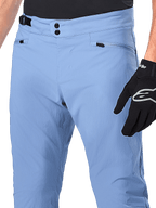 Calças Alpinestars A-Dura, calças de ciclismo MTB, Infinity Blue, grande plano da cintura com fecho duplo de pressão e ajustador lateral, bolsos com fecho de correr, usadas com luvas pretas Alpinestars