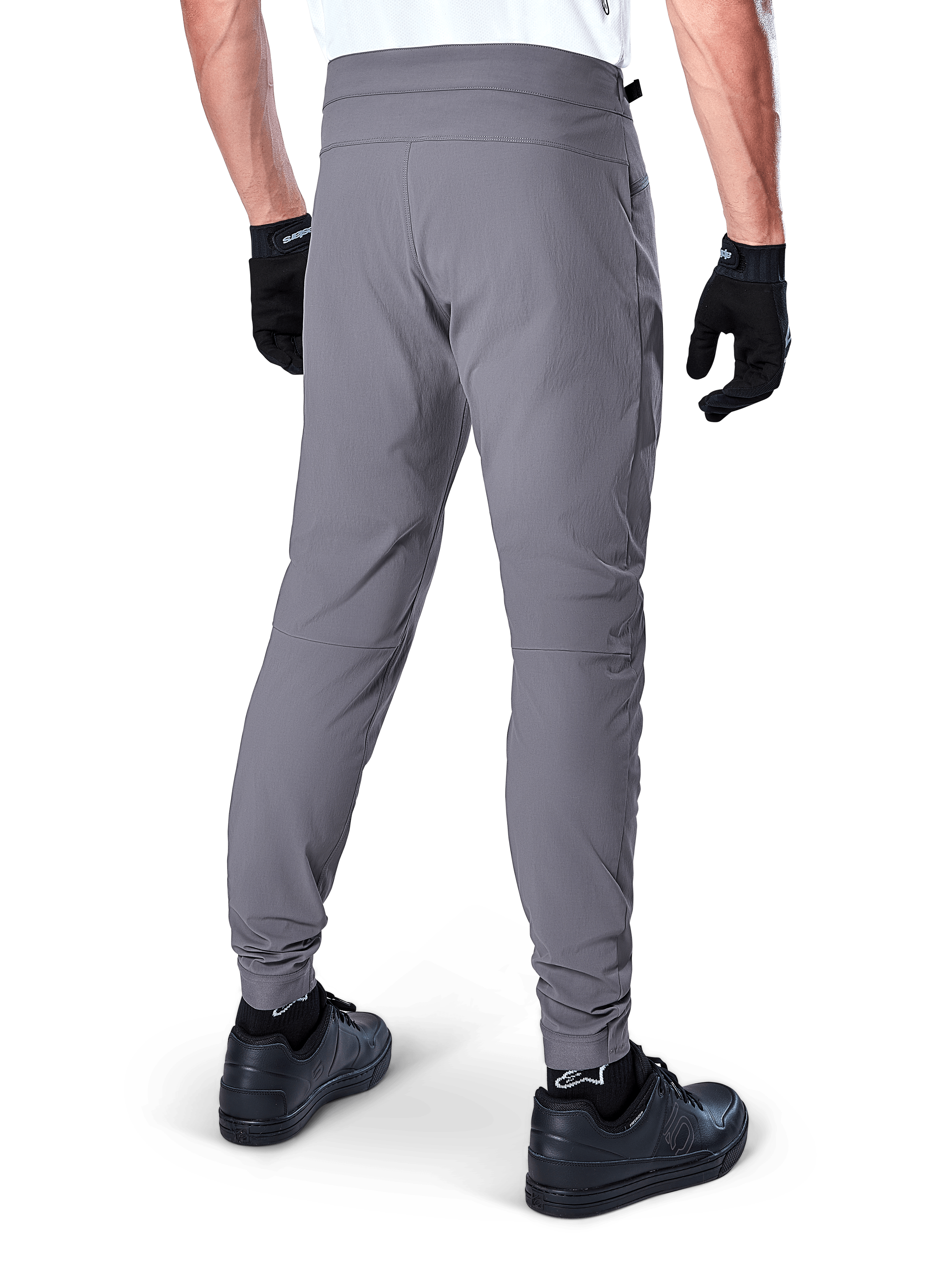 Calças Alpinestars A-Dura, calças de MTB, cinza escuro, vista traseira do modelo a usar o equipamento, com tecido durável com elasticidade em 2 direções e punhos elásticos, coordenadas com luvas e sapatilhas pretas para um visual pronto para o ciclismo