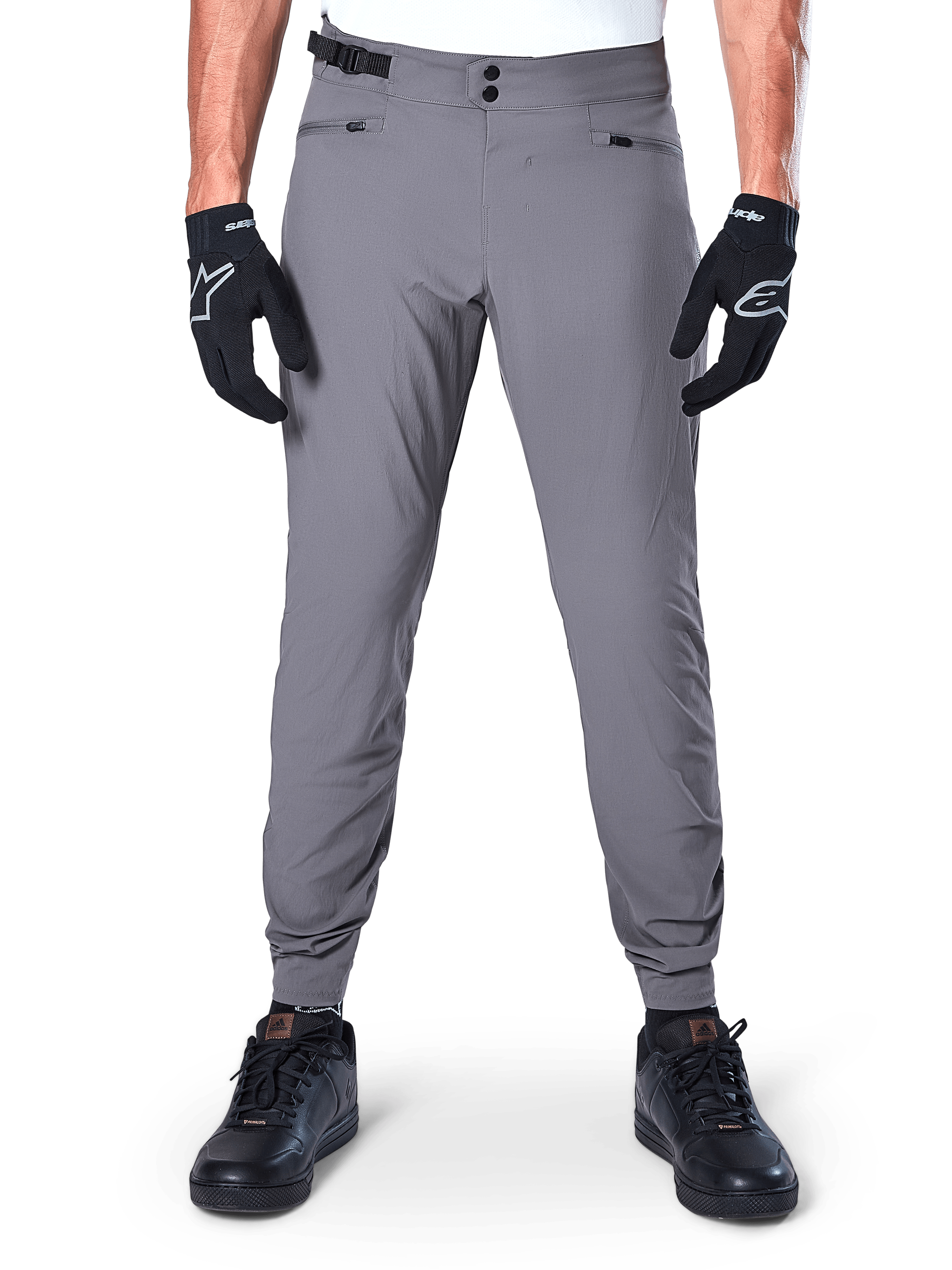 Calças Alpinestars A-Dura, calças de BTT cinzento-escuro, vista frontal, usadas com luvas pretas e ténis pretos, com fecho de cintura de pressão duplo, bolsos com fecho de correr e punhos elásticos, vestuário de ciclismo durável para trail