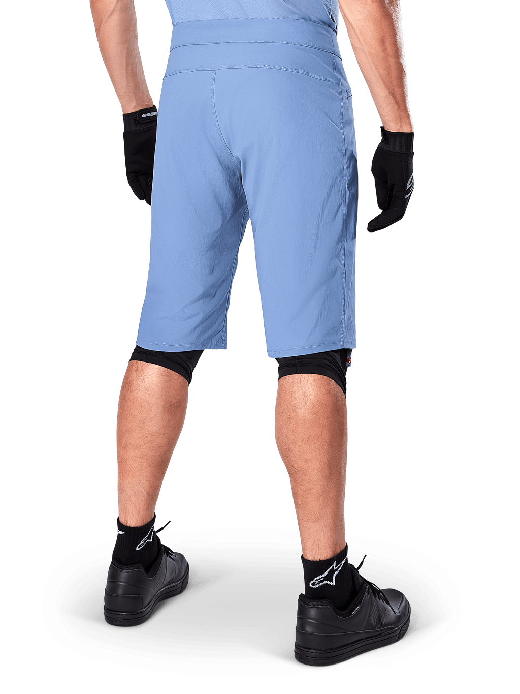 Calções Alpinestars A-Dura, calções de mountain bike Infinity Blue, vista traseira, combinados com luvas pretas, proteções de joelho e meias pretas com logótipo de estrela branco, material elástico durável para ciclismo todo-o-terreno