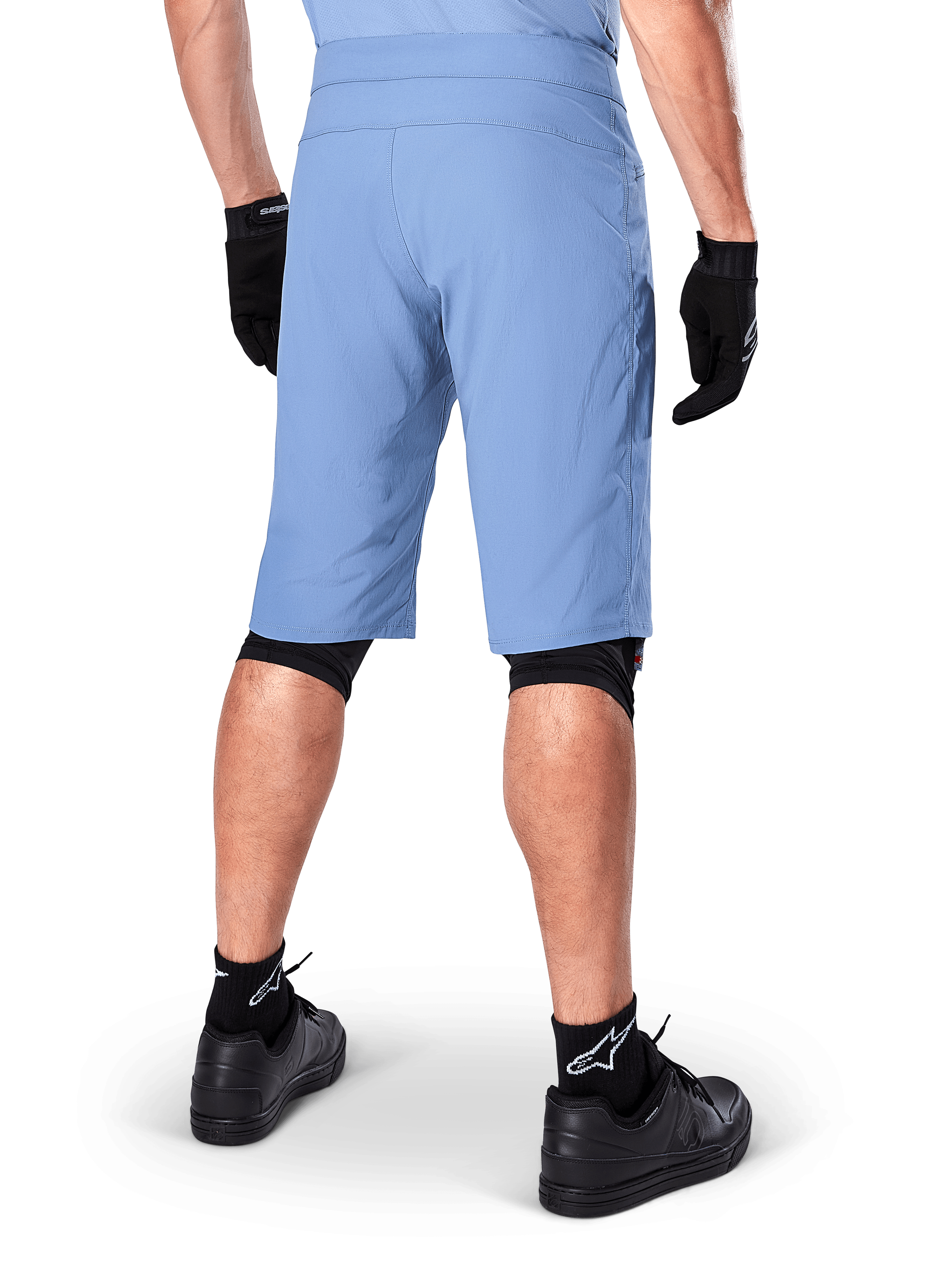 Calções Alpinestars A-Dura, calções de mountain bike Infinity Blue, vista traseira, combinados com luvas pretas, proteções de joelho e meias pretas com logótipo de estrela branco, material elástico durável para ciclismo todo-o-terreno